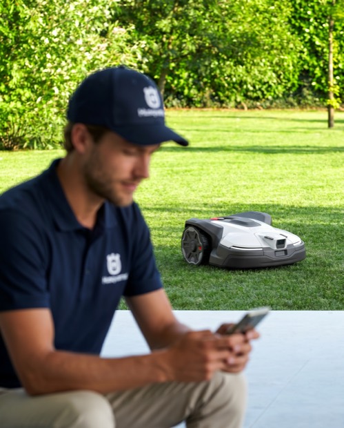 Mitarbeiter richtet einen Mähroboter im Garten ein